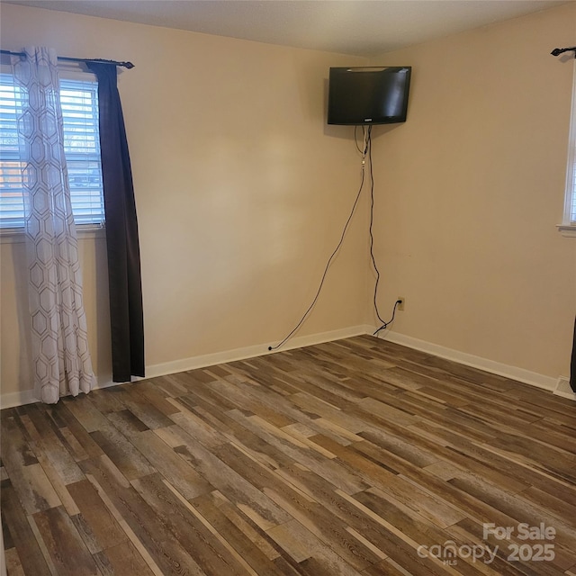 unfurnished room with baseboards and dark wood-style flooring