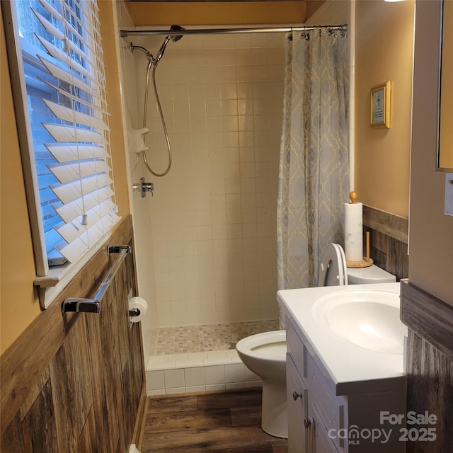 full bath featuring toilet, vanity, tiled shower, and wood finished floors