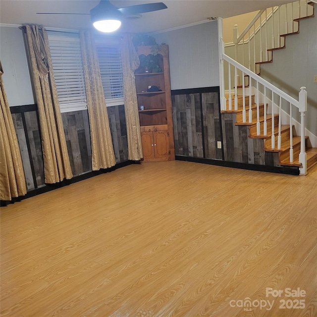 unfurnished room with a ceiling fan, stairway, ornamental molding, and wood finished floors