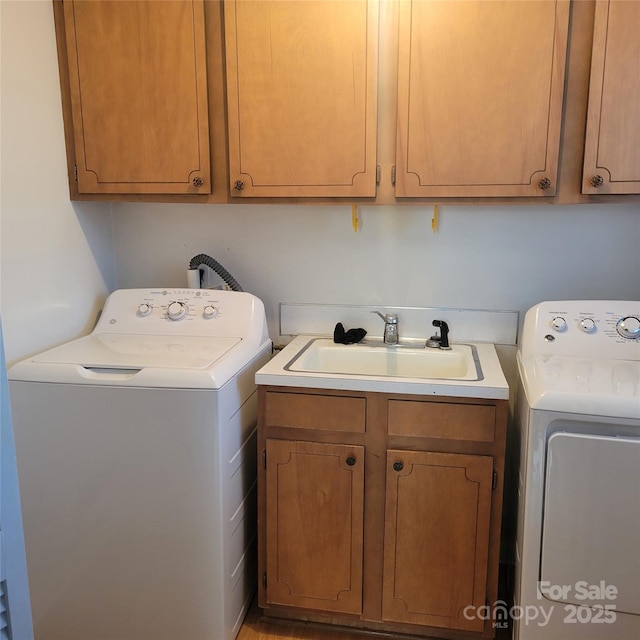 clothes washing area with independent washer and dryer, cabinet space, and a sink