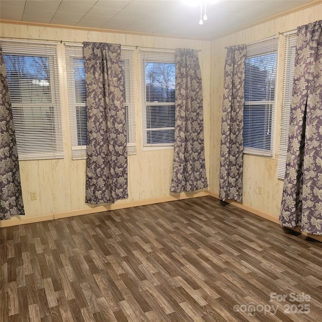 unfurnished room featuring a healthy amount of sunlight, wood walls, and wood finished floors