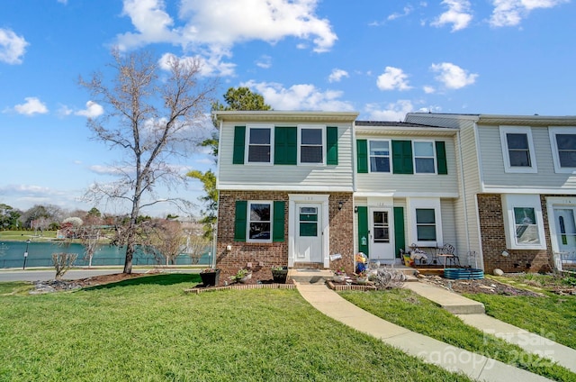 view of property with brick siding and a front yard