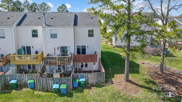 back of house featuring fence, stairs, roof with shingles, a lawn, and a deck