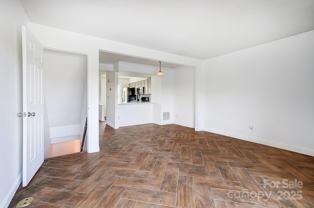 unfurnished living room with baseboards and visible vents