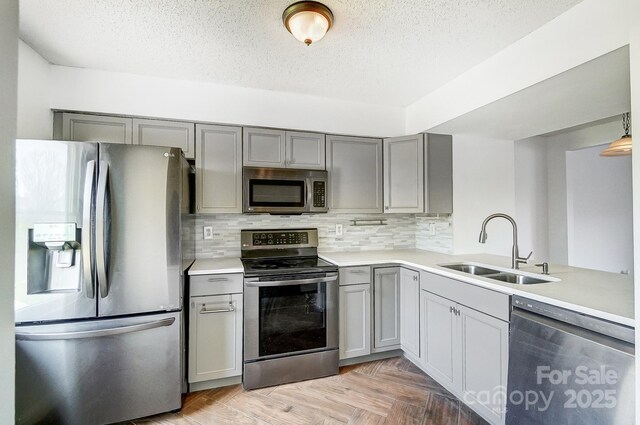 kitchen with a sink, light countertops, gray cabinetry, and stainless steel appliances