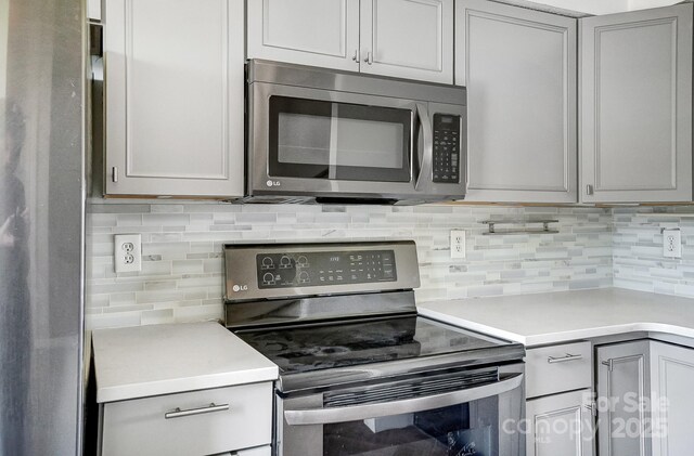 kitchen with backsplash, appliances with stainless steel finishes, gray cabinetry, and light countertops