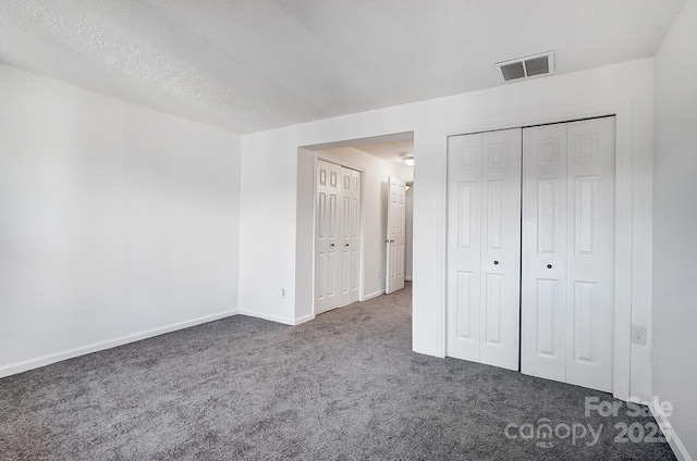 unfurnished bedroom featuring visible vents, carpet flooring, a textured ceiling, and baseboards