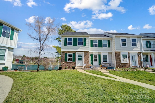 townhome / multi-family property with a front yard and brick siding