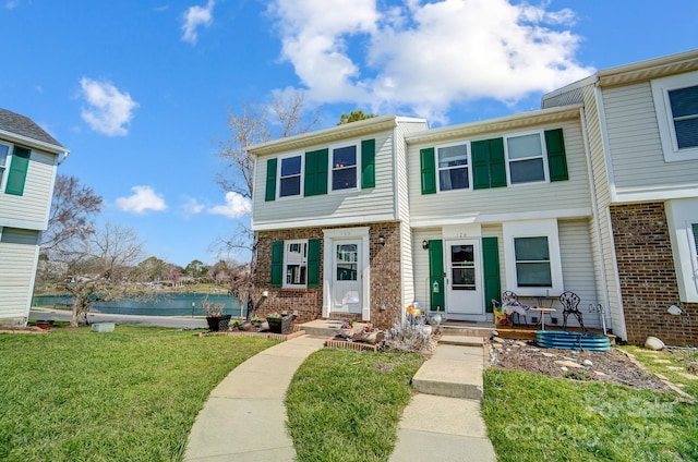 townhome / multi-family property with brick siding, a front lawn, and a water view