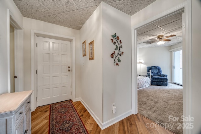 foyer featuring a ceiling fan, light wood-style flooring, a paneled ceiling, and baseboards