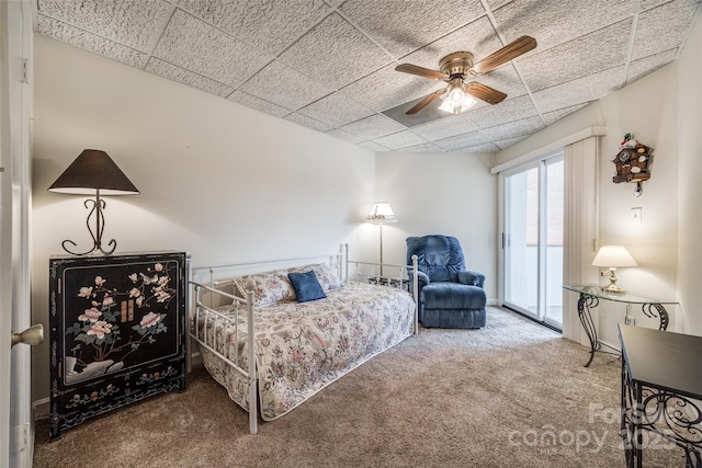 carpeted bedroom with access to exterior, a ceiling fan, and a drop ceiling