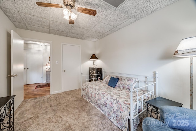 bedroom featuring a drop ceiling, carpet floors, and ceiling fan