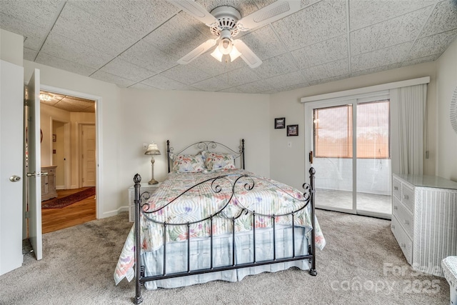 bedroom featuring a ceiling fan, access to outside, a drop ceiling, carpet flooring, and baseboards