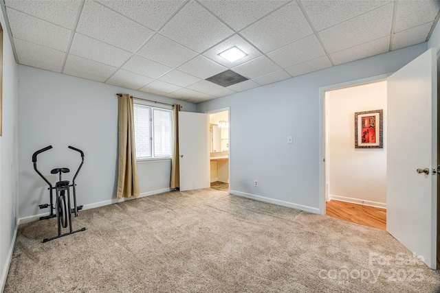 interior space with a drop ceiling, baseboards, and carpet