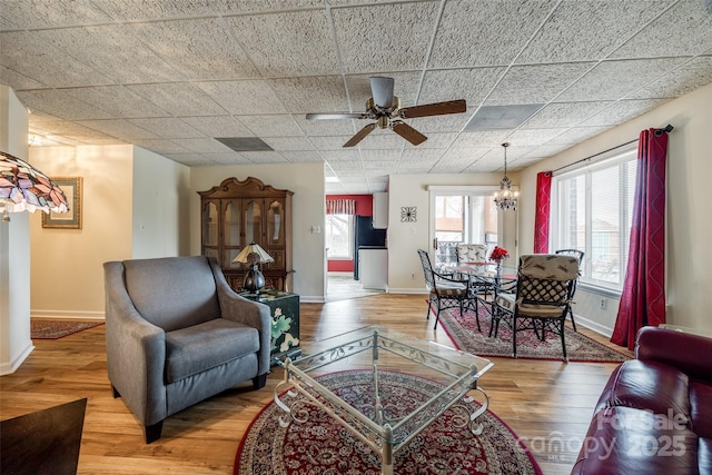 living area with wood finished floors, baseboards, and a paneled ceiling