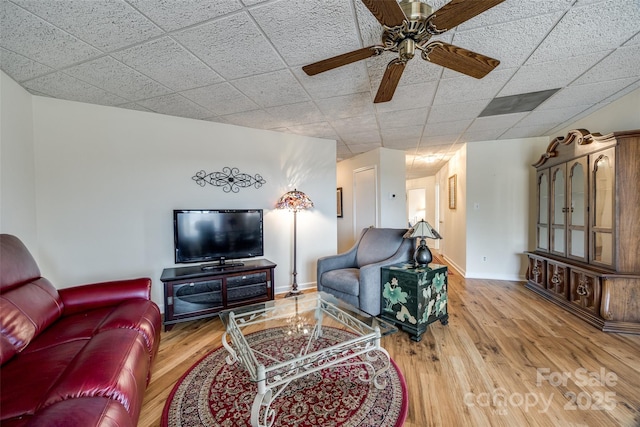 living room with wood finished floors, baseboards, and a drop ceiling