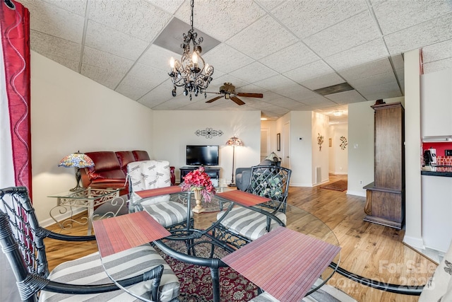 living room featuring a drop ceiling, baseboards, wood finished floors, and a ceiling fan