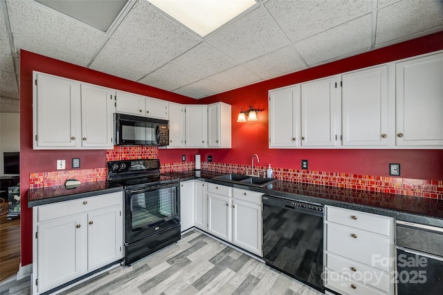 kitchen featuring white cabinetry, black appliances, dark countertops, and a sink