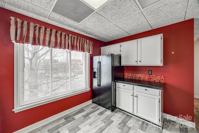 kitchen featuring dark countertops, white cabinets, a paneled ceiling, and black fridge