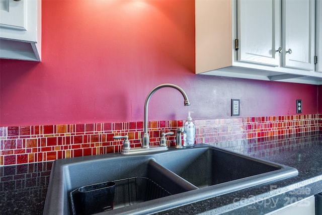 kitchen featuring a sink, tasteful backsplash, and dark countertops