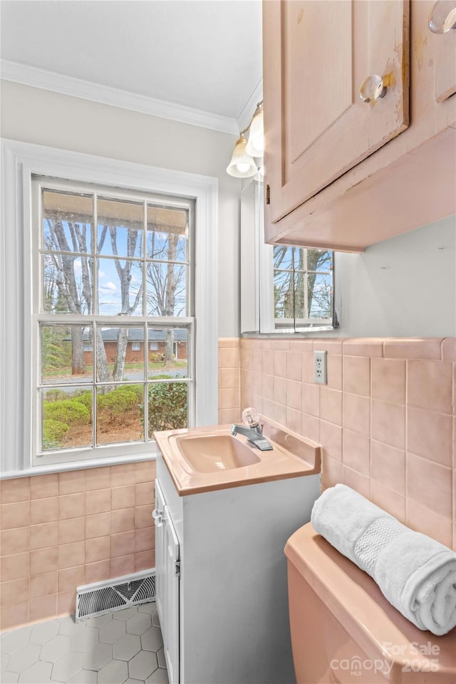 half bathroom featuring visible vents, tile walls, crown molding, tile patterned floors, and vanity