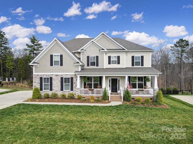 craftsman house featuring a front yard, covered porch, stone siding, and a shingled roof