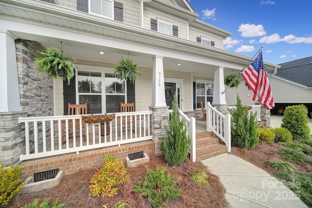 doorway to property featuring covered porch and stone siding