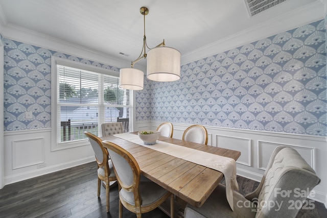 dining space with dark wood finished floors, ornamental molding, wainscoting, and wallpapered walls