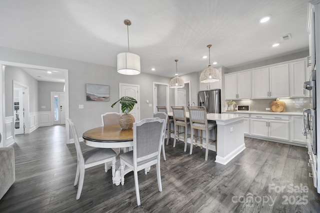 dining area with visible vents, recessed lighting, wainscoting, a decorative wall, and dark wood-style flooring