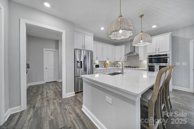 kitchen with a sink, wall chimney range hood, backsplash, stainless steel appliances, and light countertops