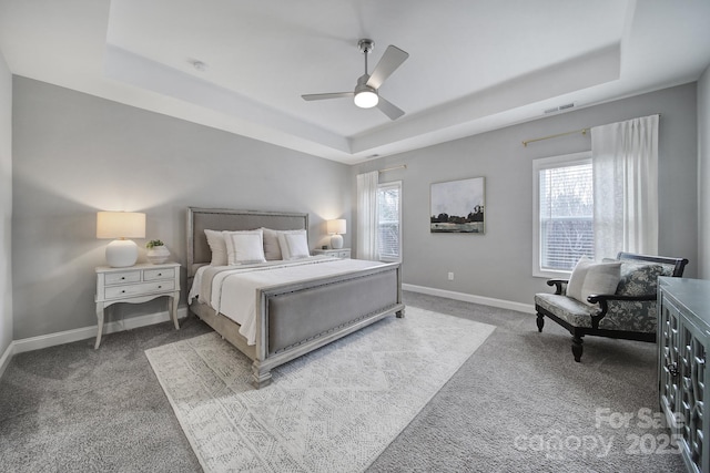 carpeted bedroom with visible vents, multiple windows, baseboards, and a tray ceiling