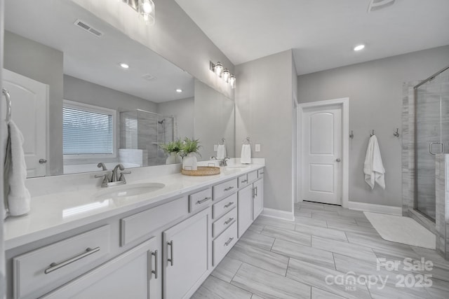 full bath featuring double vanity, visible vents, a shower stall, and a sink