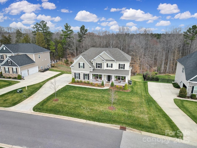 traditional-style home featuring covered porch, concrete driveway, a front yard, a shingled roof, and a garage