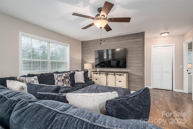 living room featuring ceiling fan, baseboards, and wood finished floors