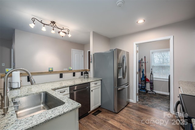 kitchen with visible vents, dark wood-type flooring, light stone countertops, stainless steel appliances, and a sink