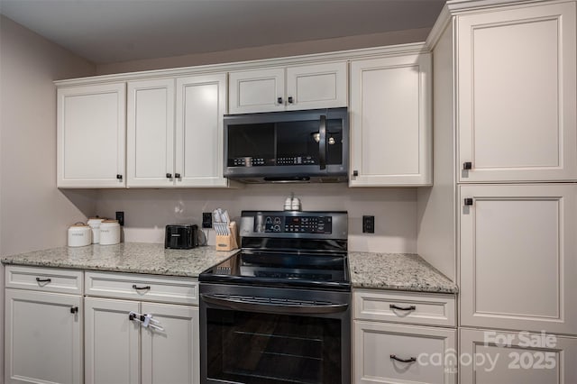 kitchen featuring white cabinetry, stainless steel microwave, light stone countertops, and electric range oven