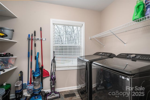 clothes washing area featuring laundry area, washing machine and dryer, and baseboards