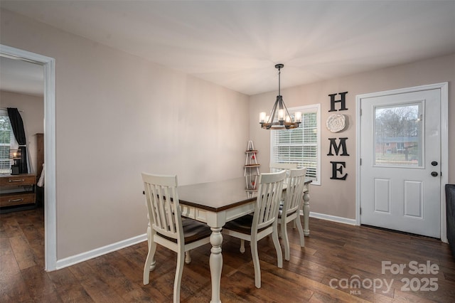 dining space featuring a chandelier, a healthy amount of sunlight, dark wood-type flooring, and baseboards