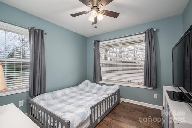 bedroom featuring a ceiling fan, multiple windows, baseboards, and dark wood-style flooring