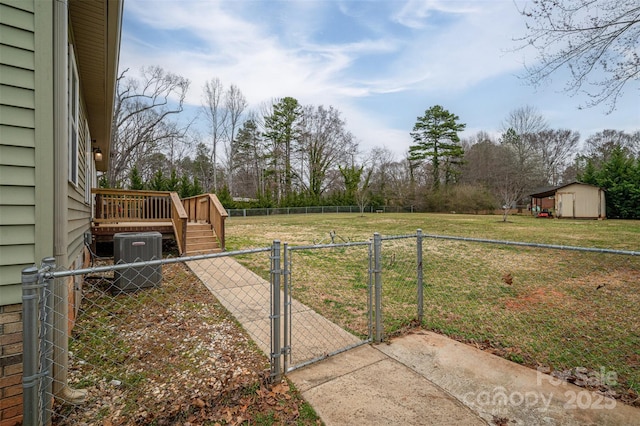 view of yard featuring fence private yard, central AC, an outbuilding, a storage unit, and a gate