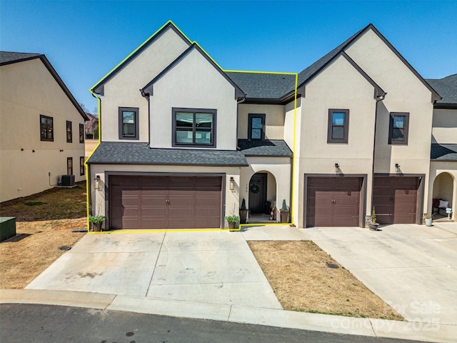 view of front of home with stucco siding, driveway, central AC, and a garage