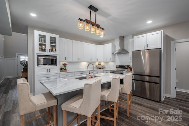 kitchen featuring a sink, stainless steel appliances, white cabinets, and wall chimney range hood