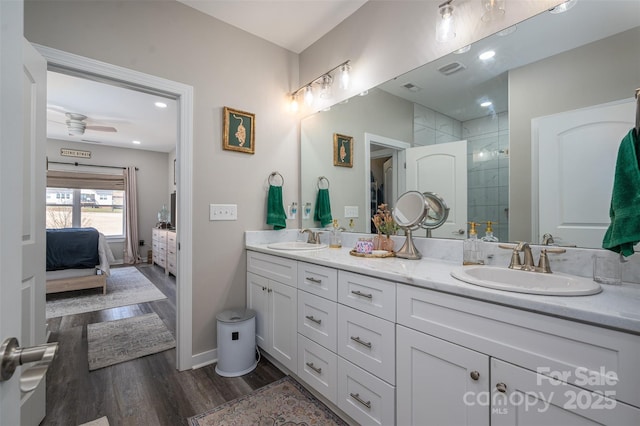 ensuite bathroom featuring ensuite bath, wood finished floors, a tile shower, and a sink