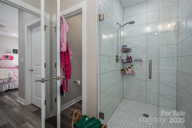 ensuite bathroom featuring baseboards, wood finished floors, a stall shower, and ensuite bathroom