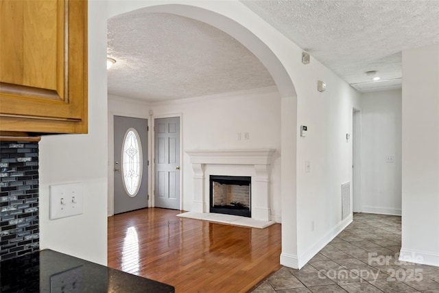 interior space featuring wood finished floors, visible vents, baseboards, a fireplace with raised hearth, and a textured ceiling