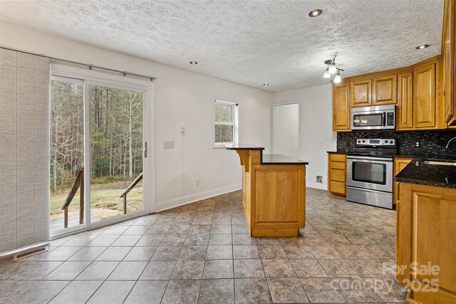 kitchen featuring visible vents, backsplash, appliances with stainless steel finishes, plenty of natural light, and a sink