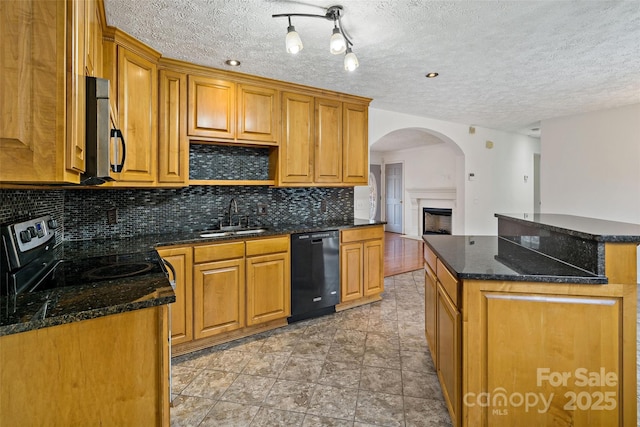 kitchen featuring a sink, decorative backsplash, appliances with stainless steel finishes, brown cabinets, and a center island