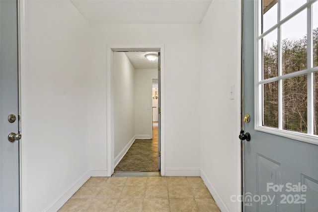 foyer entrance with light tile patterned floors, plenty of natural light, and baseboards