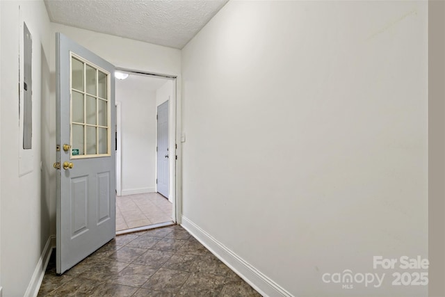 hall with baseboards and a textured ceiling