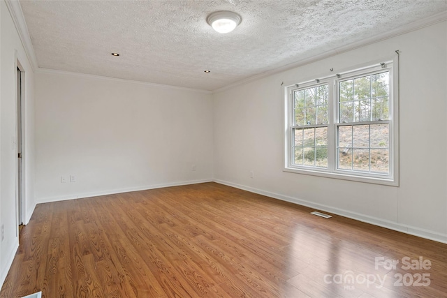 unfurnished room featuring visible vents, crown molding, baseboards, and wood finished floors